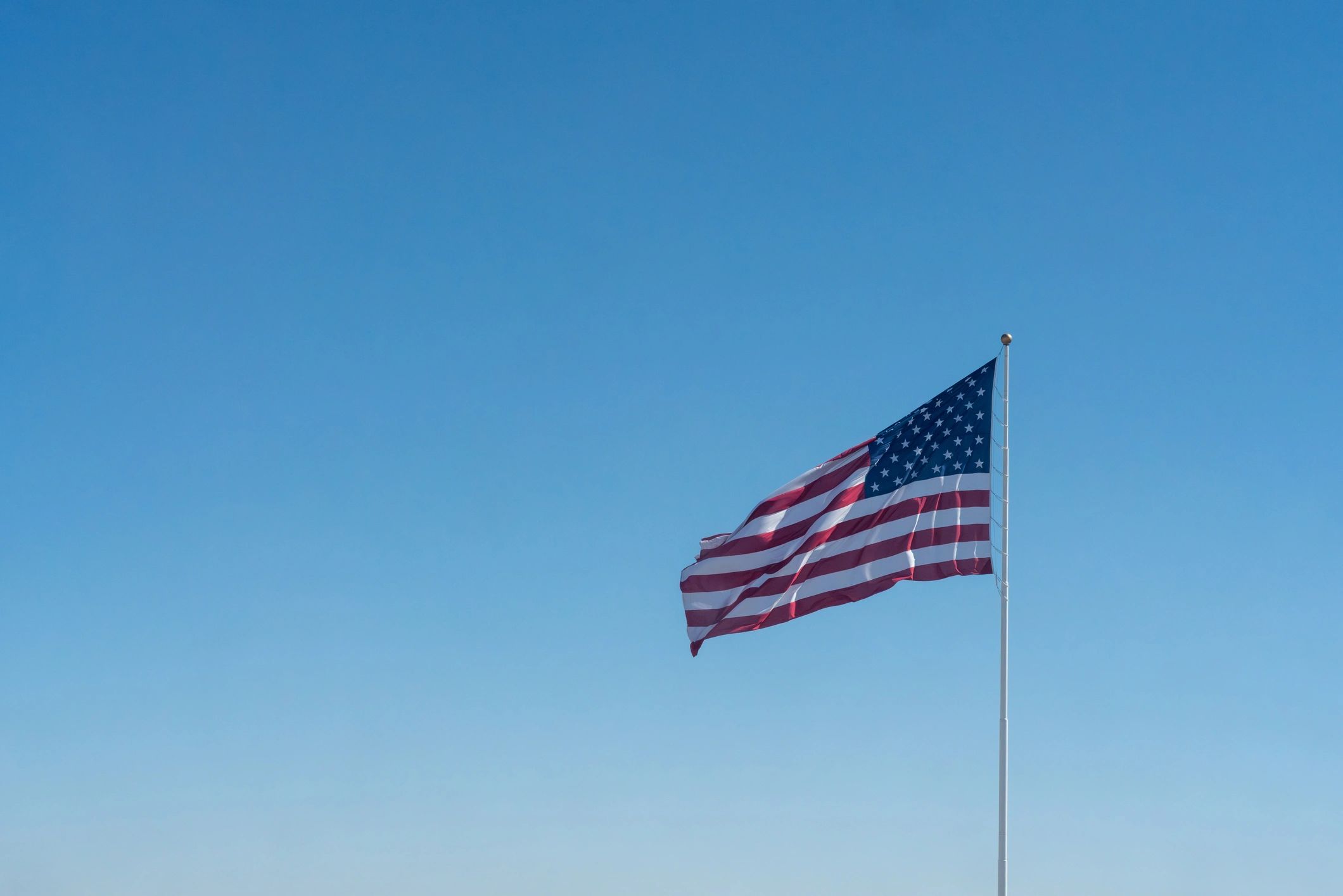 United States flag waving against a clear blue sky